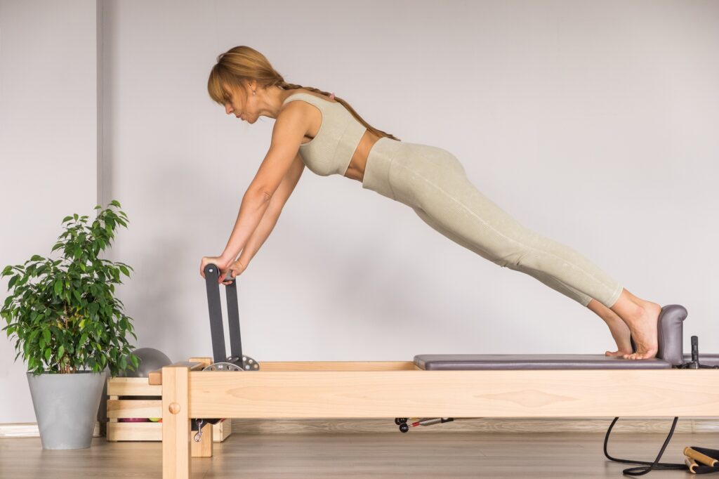 Woman training pilates on the reformer bed. Reformer pilates studio machine for fitness workouts in